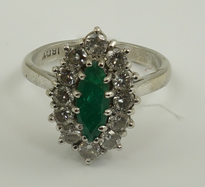 A modern 18ct white gold and single stone marquise cut emerald set ring, bordered with round brilliant cut diamonds